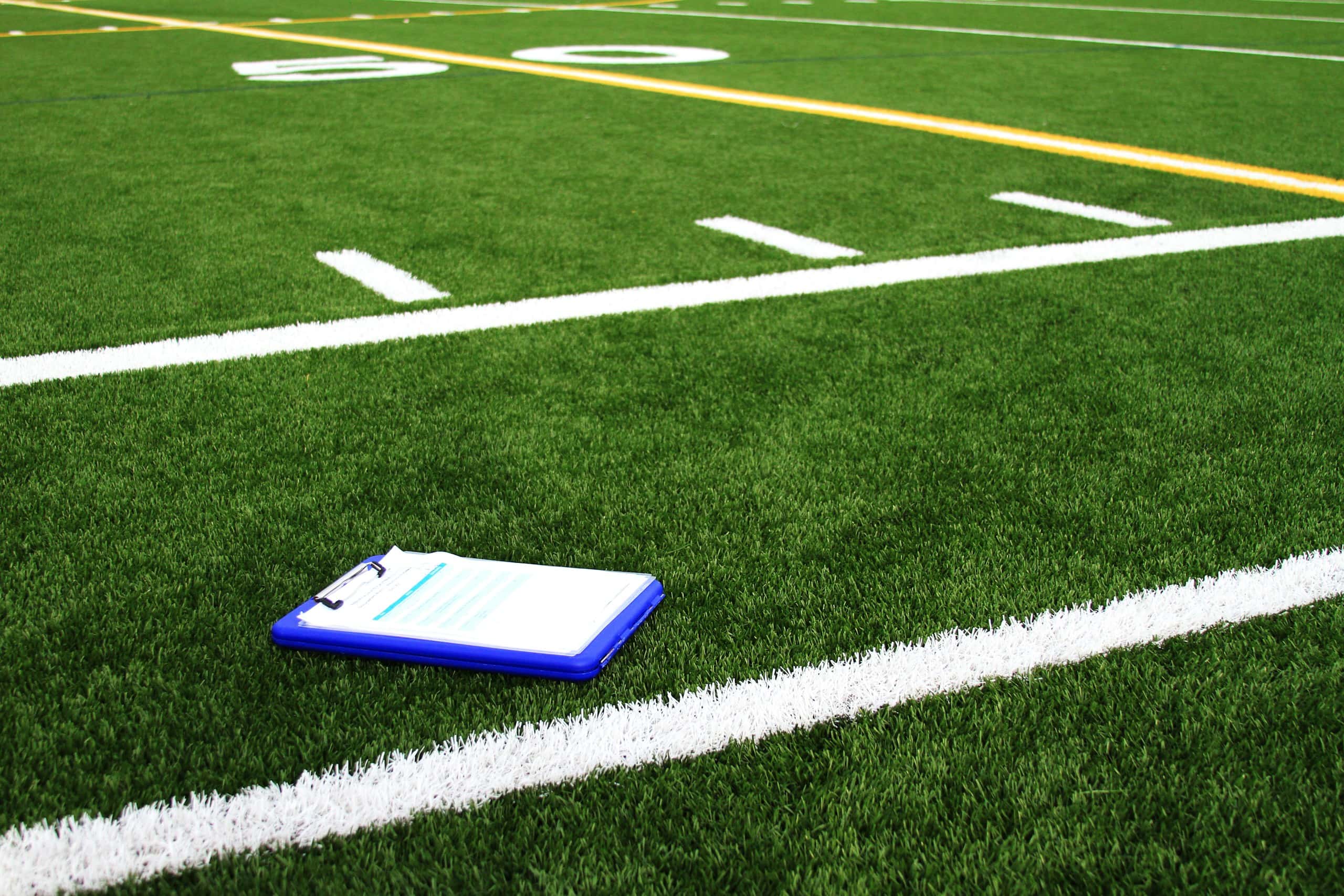 A clipboard resting on the line of a football field